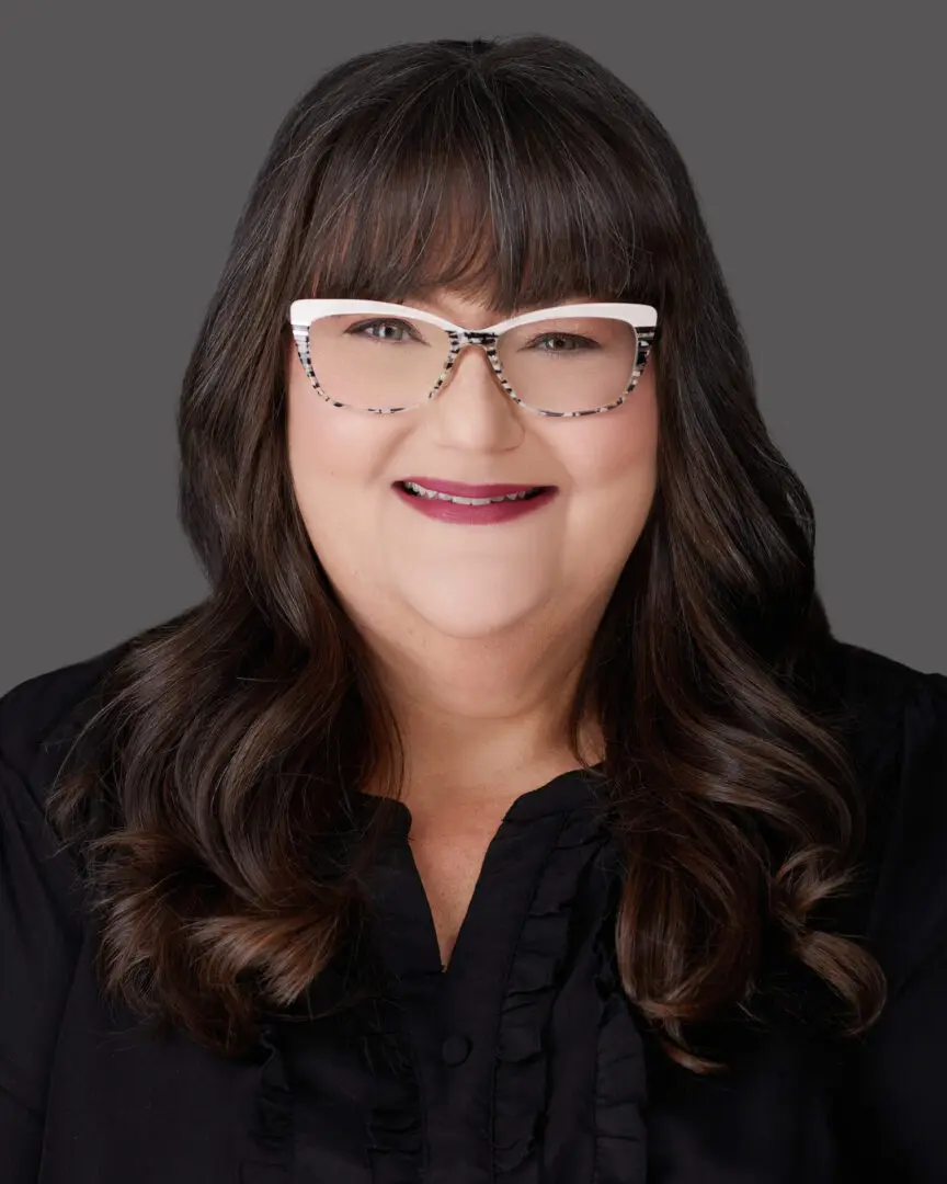 A woman with glasses and long hair wearing a black shirt.