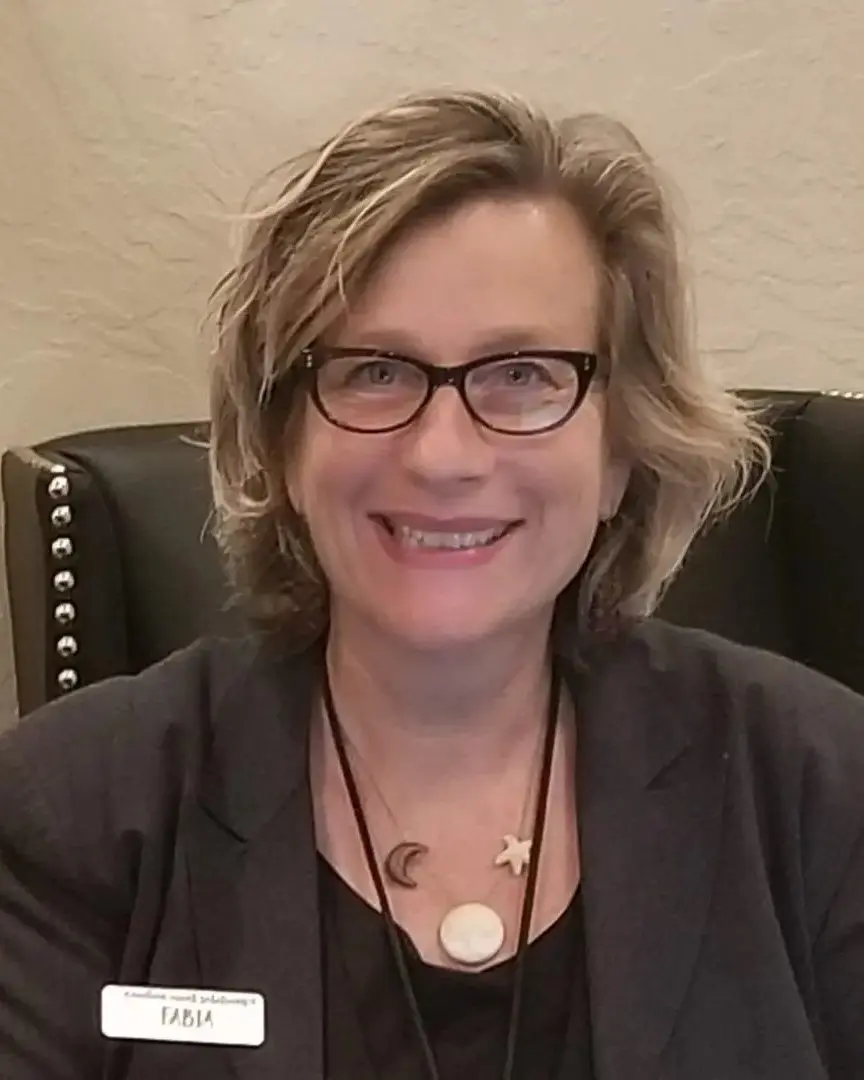 A woman with glasses sitting in a chair.